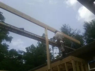 Carpenter setting a ridge beam over a new addition frame — Ice Dam Removal by Roofing Brothers in Trinity Center