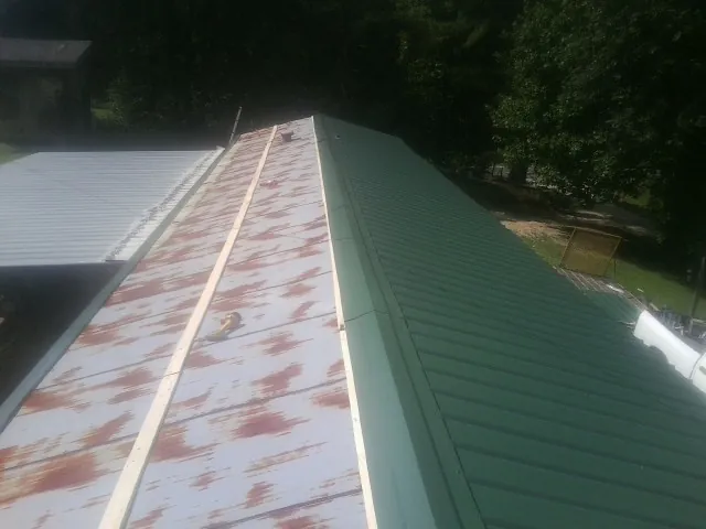 Old rusted panels beside newly installed green metal roofing — Wind Damage Roof Repair by Roofing Brothers in Trinity Center