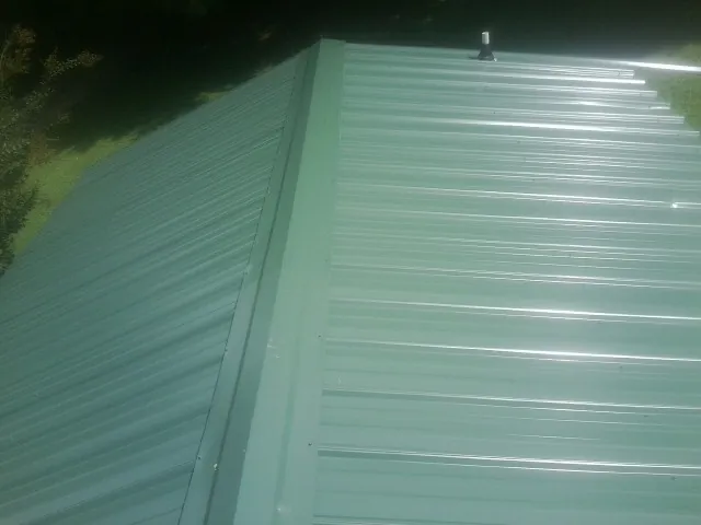 New green metal panels meeting at the ridge of a roof — Flat Roof Repair work by our crew in Trinity Center